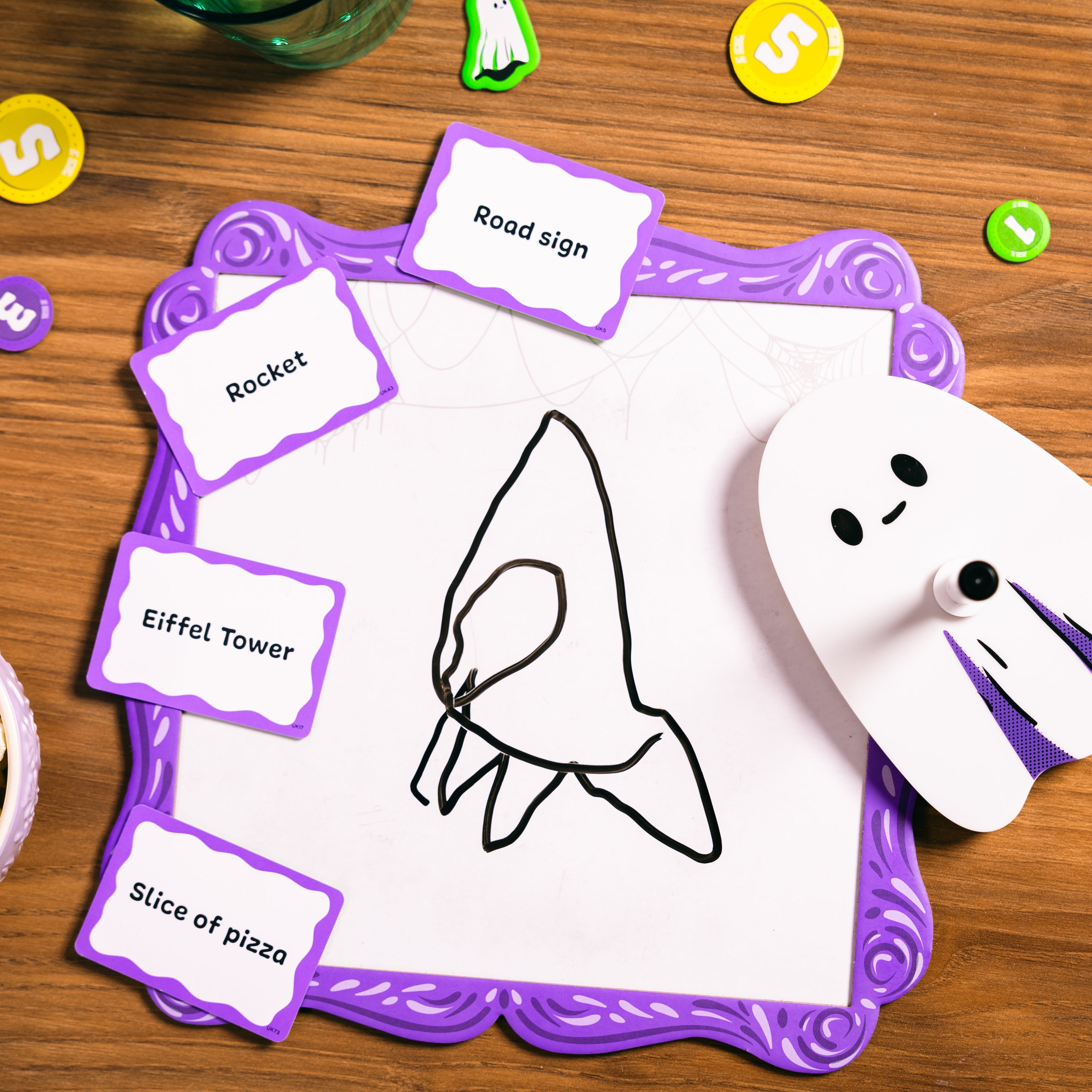 Board game with cards and a ghost cutout on a wooden table.