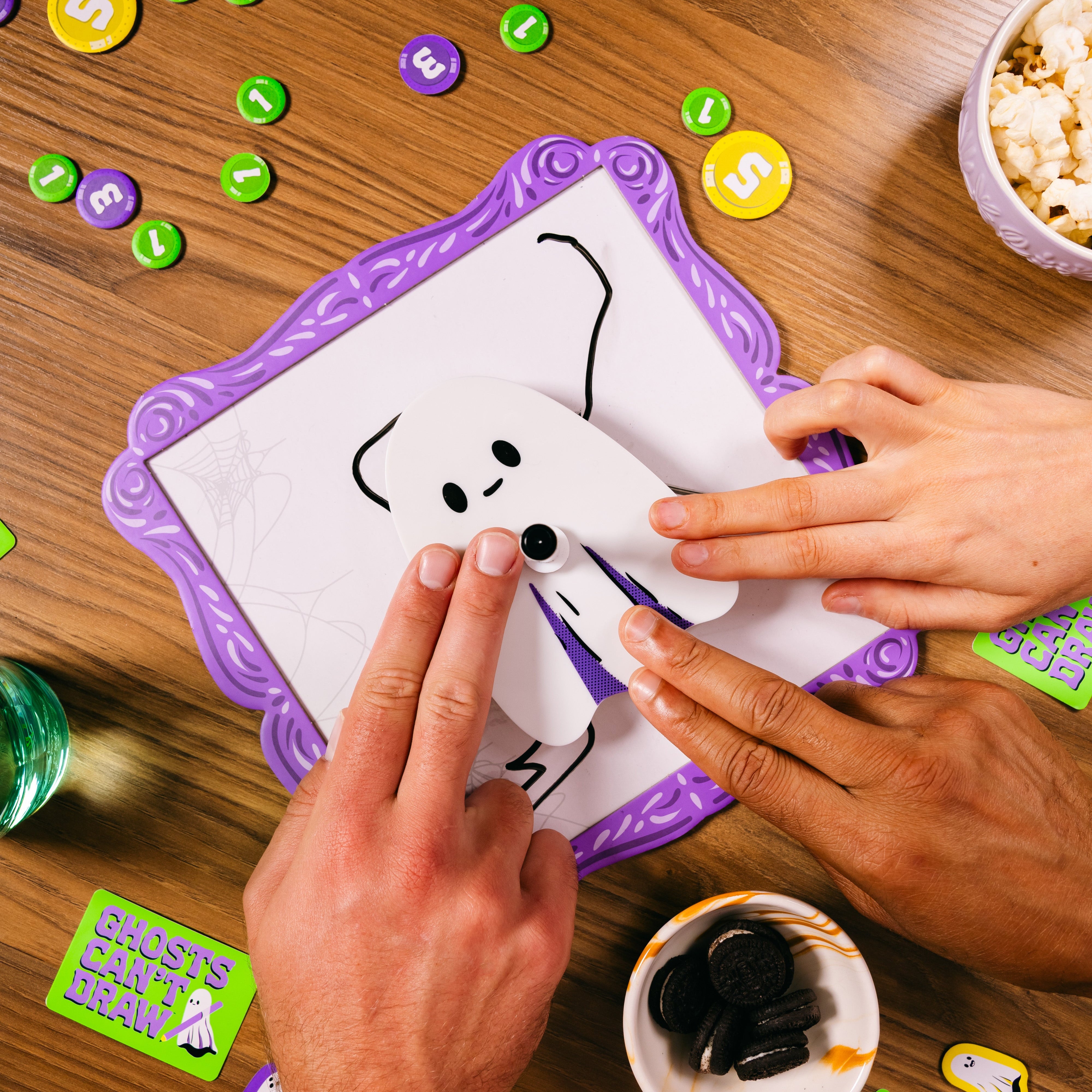 Two hands interacting with a game on a wooden table.