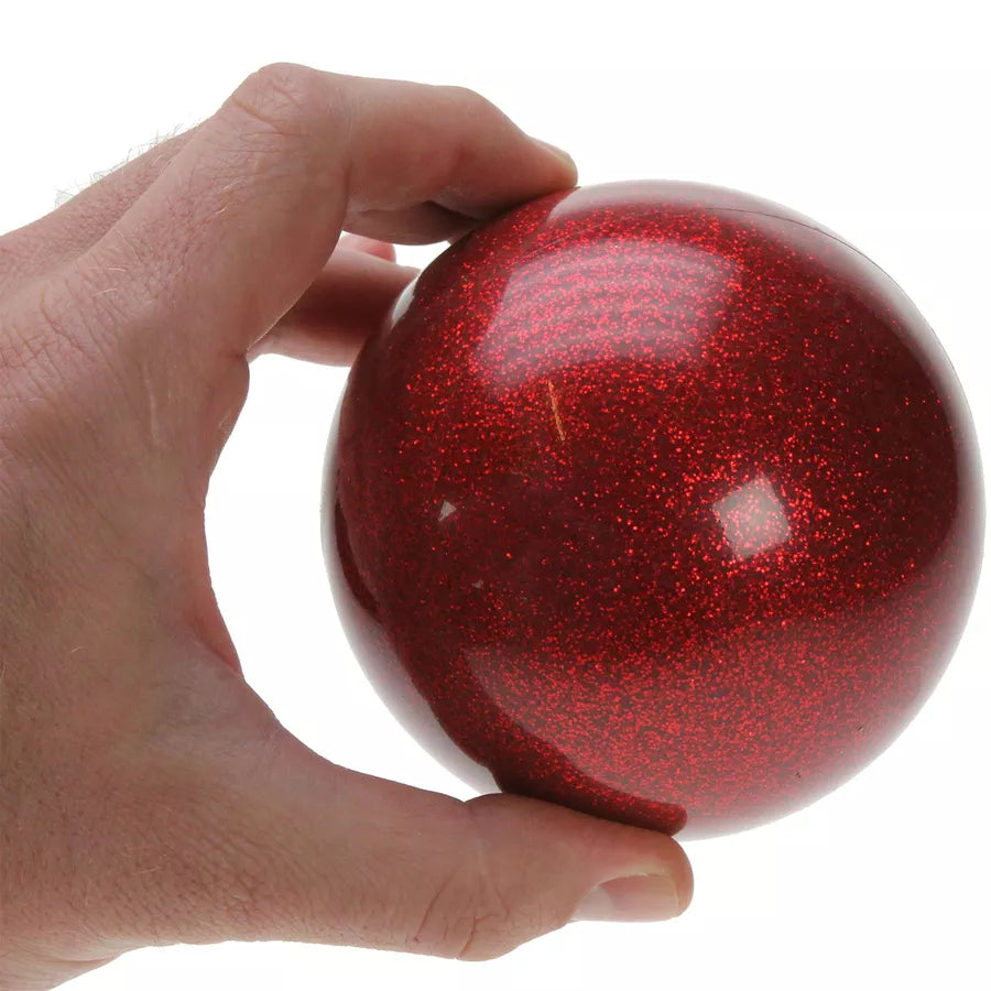 A hand holding a 100mm red glitter stage ball