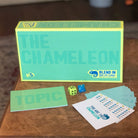 Board game components including a box, cards, dice, and printed materials on a wooden surface.