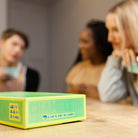 Green game box on a table with people in the background