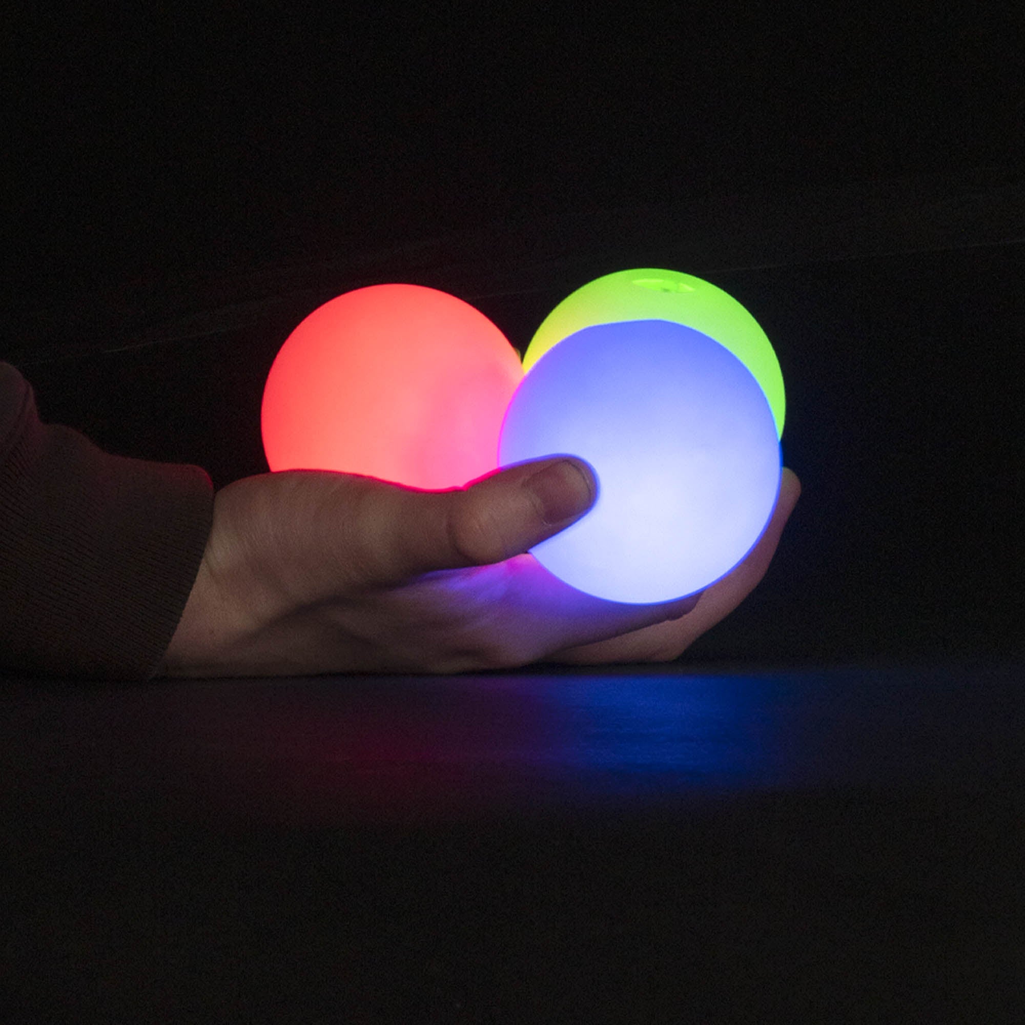 Red, blue and green glowing juggling balls in hand