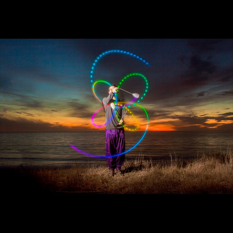 Flowtoys Podpoi v2 light trails with many colours and the sunset and ocean in the background